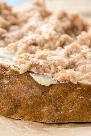 Fish pate spread on a slice of bread on the wrinkled brown paper.の写真素材