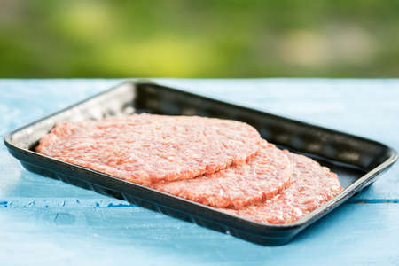 Minced meat burgers in the market package above wooden background.