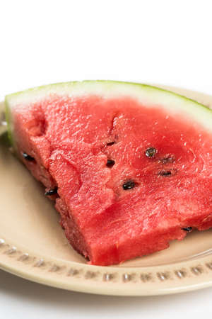 Triangle slice of watermelon on the plate isolated over white background.