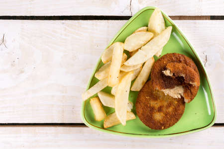 Fried fish meat burgers served with french fries on the plate.