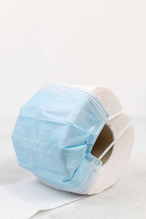 Toilet paper with blue protective surgical mask with copy space.
