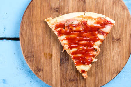 Flat lay above fresh baked pizza triangle slice on the wooden board with cutting knife.の写真素材