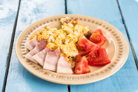 Fried eggs with sliced tomato salad and domestic bacon.の写真素材