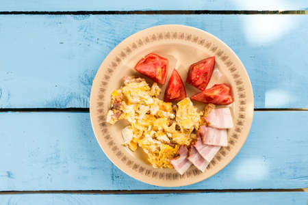 Flat lay breakfast fried eggs with raw bacon and tomato salad.の写真素材