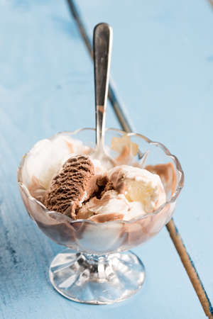 Vanilla and chocolate ice cream in the crystal bowl on the wooden planks.