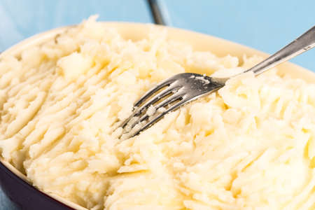 Mashed potatoes in the bowl on the wooden planks table.