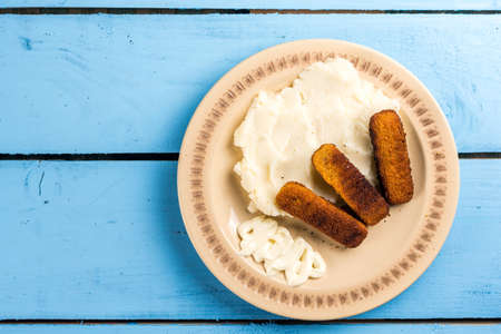 Flat lay mashed potatoes served with fish meat sticks on the plate.の写真素材