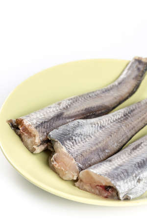 Raw hake on the plate above white background.