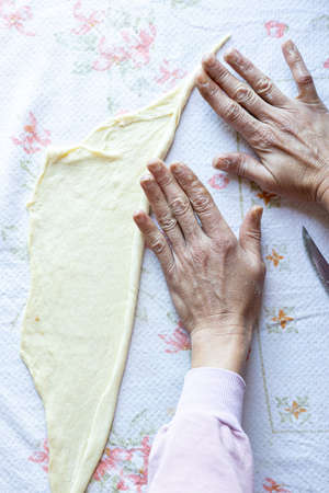 Top view of woman hands rolling raw dough preparing for baking.の写真素材