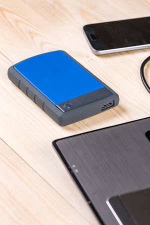 External hard disc hdd on the wooden table with lap top computer and mobile phone.