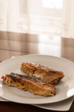Flat lay fried grilled paprika in the eggs served on the white plate above brown table boards.の写真素材