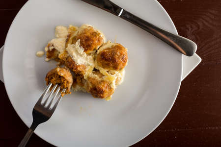 Flat lay above sliced meatballs with cheese served on the plate.
