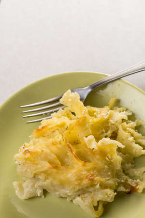 Gratinated macaroni with cheese served on the green plate.