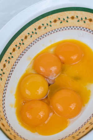 Raw eggs yolks in the bowl on the table.