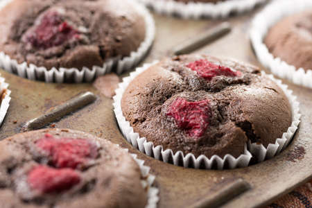 Selective focus on baked chocolate cup cake with raspberries.