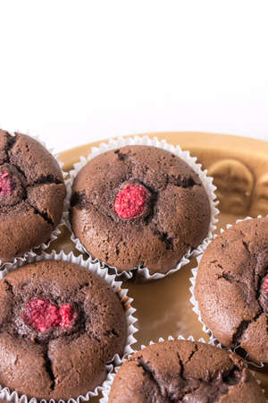 Flat lay above plate with chocolate cup cake muffins with raspberries with white copy space background.の写真素材