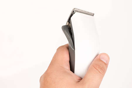 White haircut trimmer in the hand above white background with copy space.