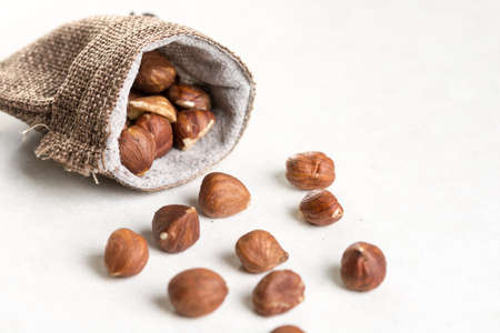Raw hazelnuts on white background and jute drawstring pouches bag.の写真素材
