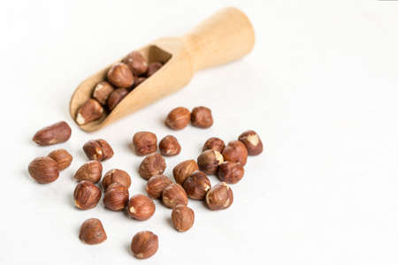 Raw hazelnuts on the white background with wooden spatula spoon.