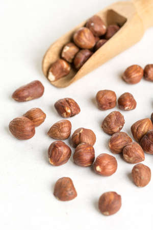 Raw hazelnuts on the white background with wooden spatula spoon.の写真素材