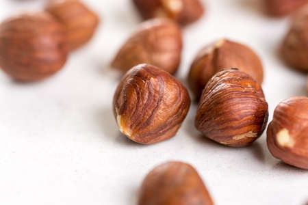 Closeup macro of raw hazelnuts on the white marble background.の写真素材