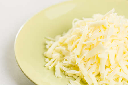Macro of grated cheese pile on the green plate.