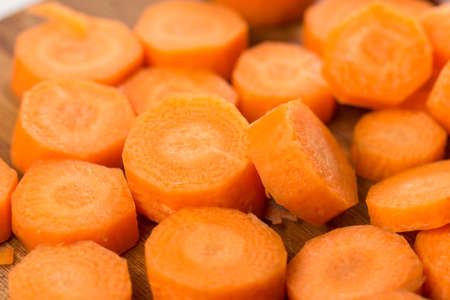 Pile of sliced and chopped carrot on the wooden board.
