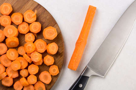 Chopped carrot on the wooden board with chef knife.