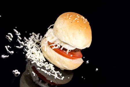 Meatball in a bun with tomato mayonnaise and grated cheese on the black background.の写真素材