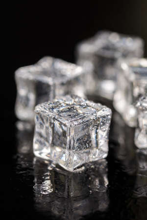 Ice cubes with drops of water on the black background with reflections.の写真素材