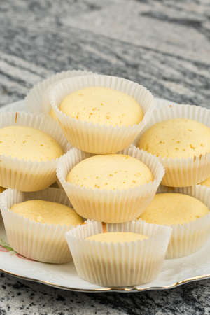 Yellow vanilla cupcakes served on the plate above grey marble.