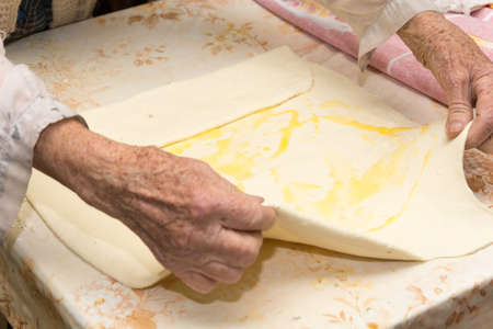 Grandmother making puff pastry on the table.