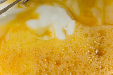 Mixed eggs with yogurt in the bowl with wire.の写真素材