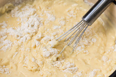 Mixed eggs with flour and oil in the metal bowlの写真素材