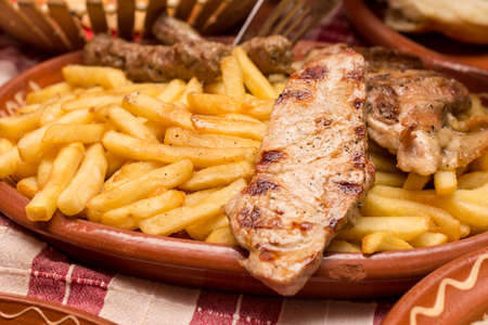 French fries with chicken white meat on the grill.