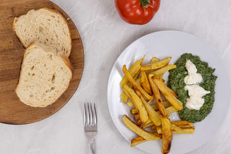Top view of french fries with spinach on the plate and sliced bread.の写真素材