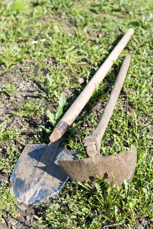 Old hoe and shovel on the grass and weeds.