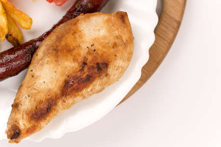 Chicken breasts and grilled red sausages on the plate.の写真素材