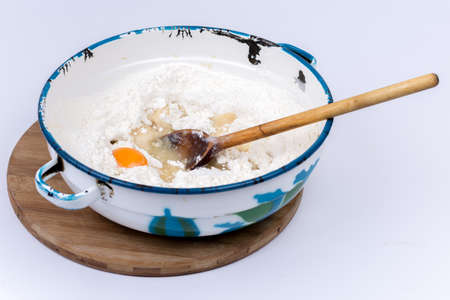 Raw egg in the flour with wooden scoop.