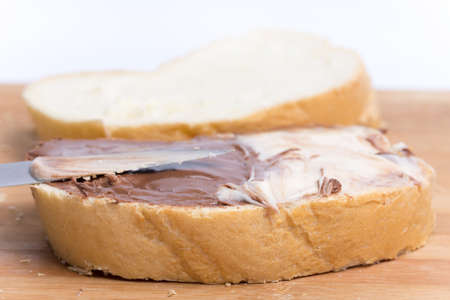 Chocolate hazelnuts cream on the bread, closeup macro image.