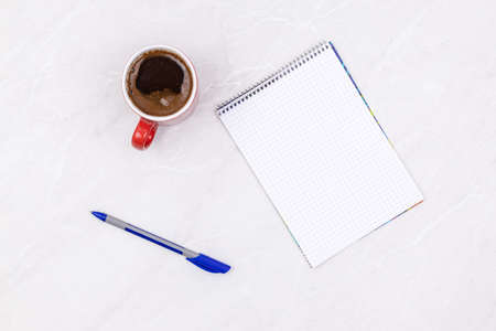 Top view of blank notepaper with pencil and cup of coffee above white background business workspace.