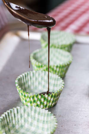 Pouring chocolate cream for muffins in paper wrappers
