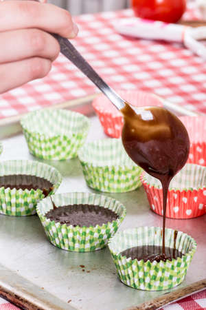 Pouring chocolate cream in the paper muffin wrappers