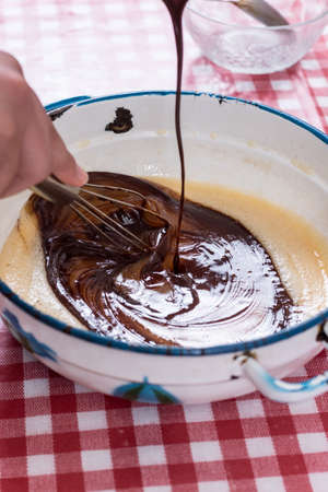 Pouring chocolate cream in raw eggs creamの写真素材