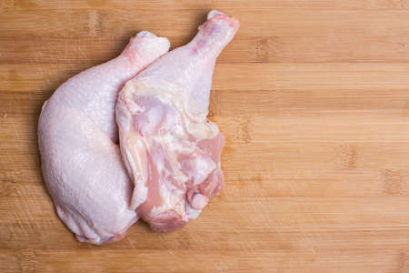 Raw chicken drumsticks on kitchen wooden board