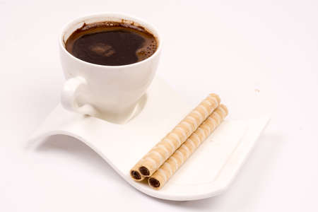 White cup of coffee with wafer chocolate cream rollsの写真素材