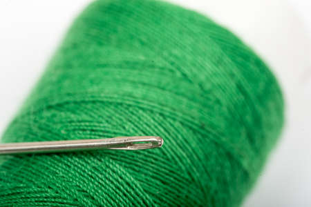 Needle head on the green thread over white backgroundの写真素材