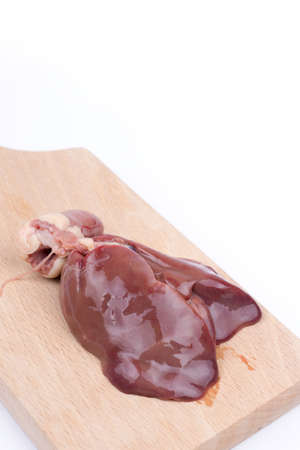 Raw chicken liver on the wooden cutting board over white background