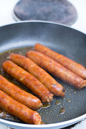 Frying homemade red sausages in frying panの写真素材