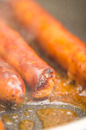 Frying homemade red sausages in frying panの写真素材